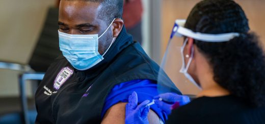 COVID单位护士Tonychris“ TC” Nnaka，（左）在12月15日在Parkland医院举行的媒体活动中，从职业健康总监Stephanie Collins那里接受了辉瑞的COVID-19疫苗接种。