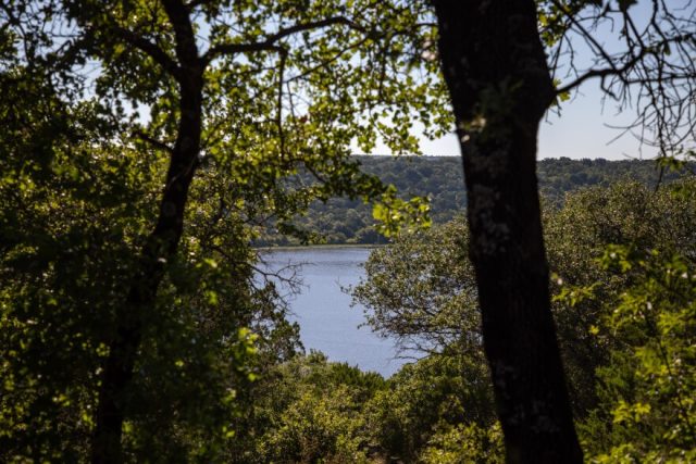 綠色的樹葉為遠處一個光滑的灰藍色湖泊提供了一個小窗口。 湖被青山環繞。